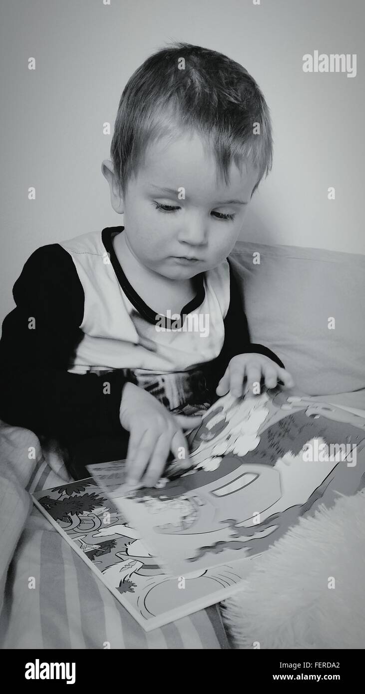 Bebé Mirando libro ilustrado sobre la cama Foto de stock