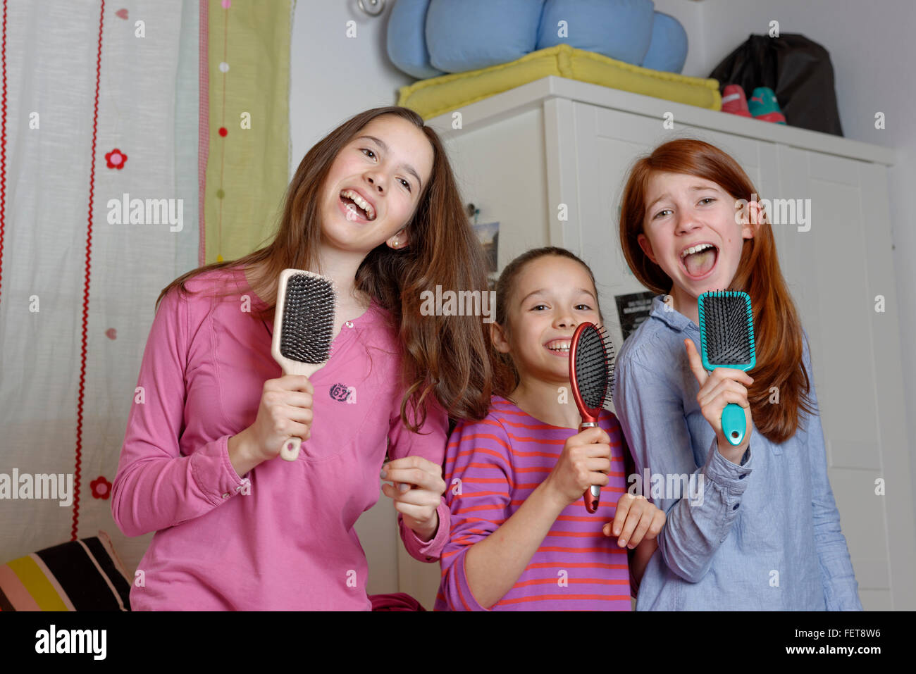 Las niñas, los niños cantando en cepillo como micrófono, Alemania Foto de stock