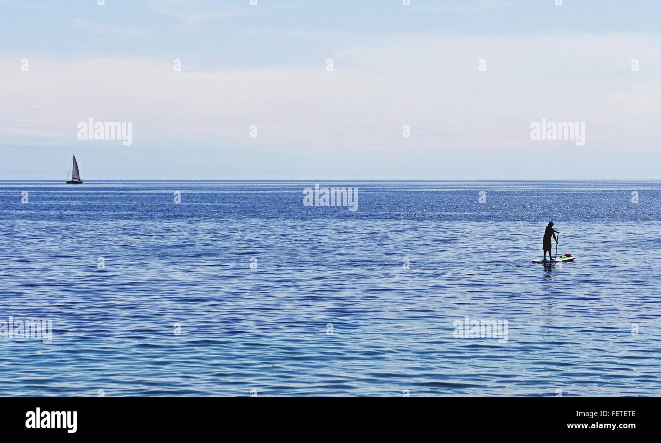 Tranquilo paisaje marítimo, Barco y surfista, el horizonte sobre el agua Foto de stock