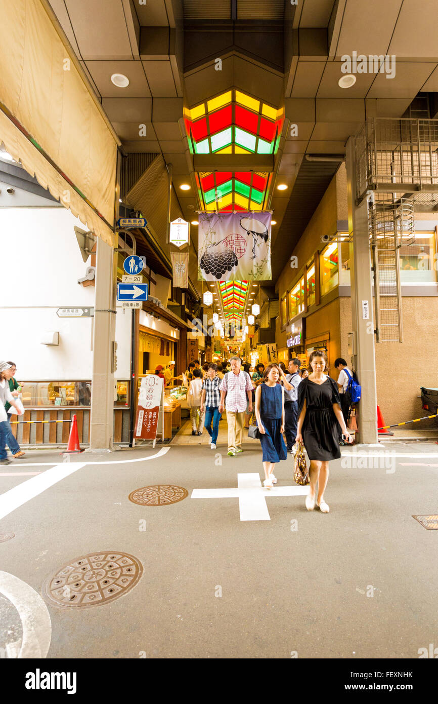 Los turistas, la gente local caminando a través de la intersección de la calle interrumpiendo la longitud del famoso mercado de Nishiki interiores comida sta. Foto de stock