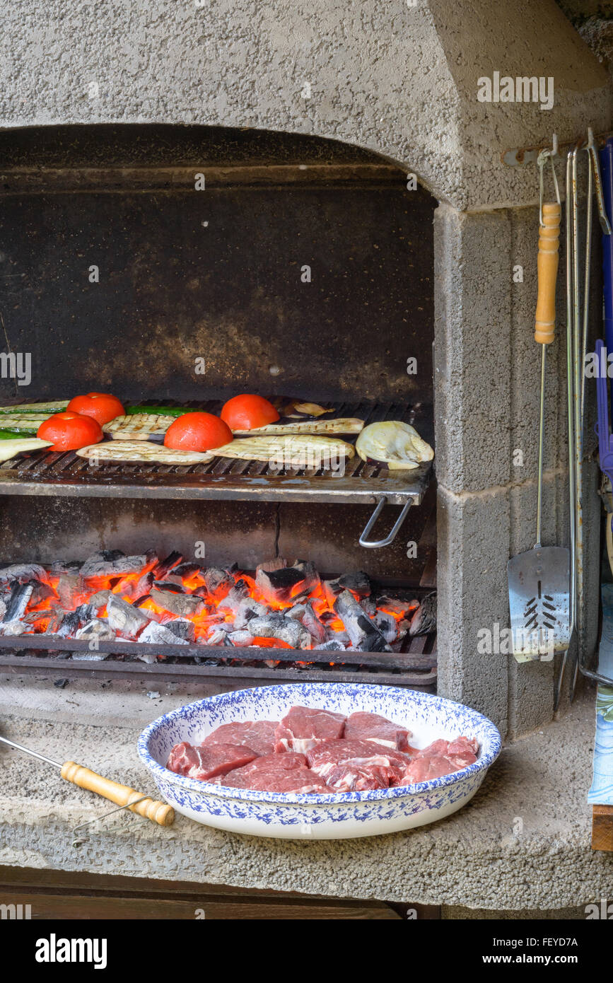Cocinar las verduras en la parrilla, tomates, calabacines, berenjenas, con un plato de carne de vacuno a la espera de ser cocinados Foto de stock