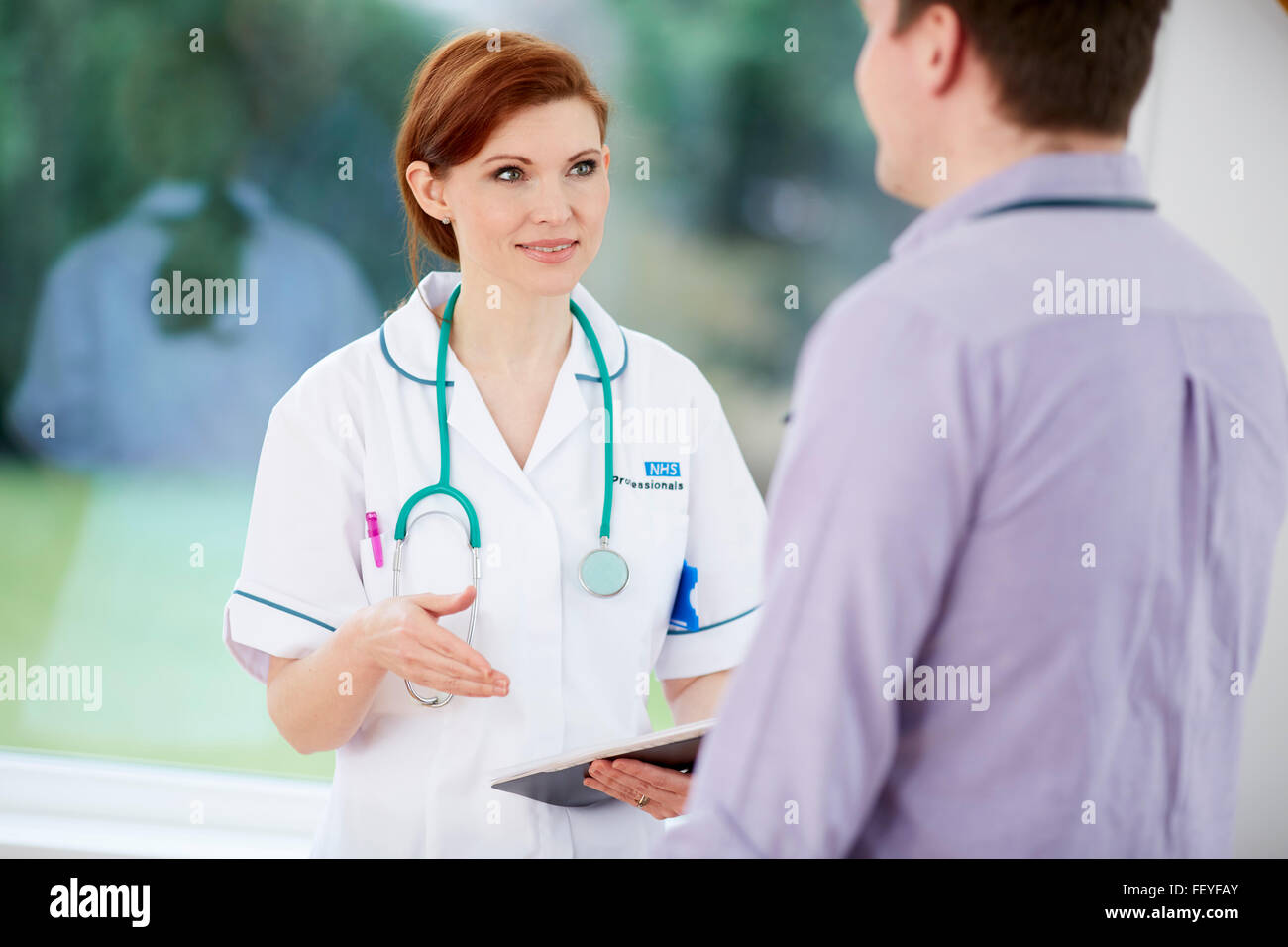 Un médico y una enfermera discutiendo notas Foto de stock