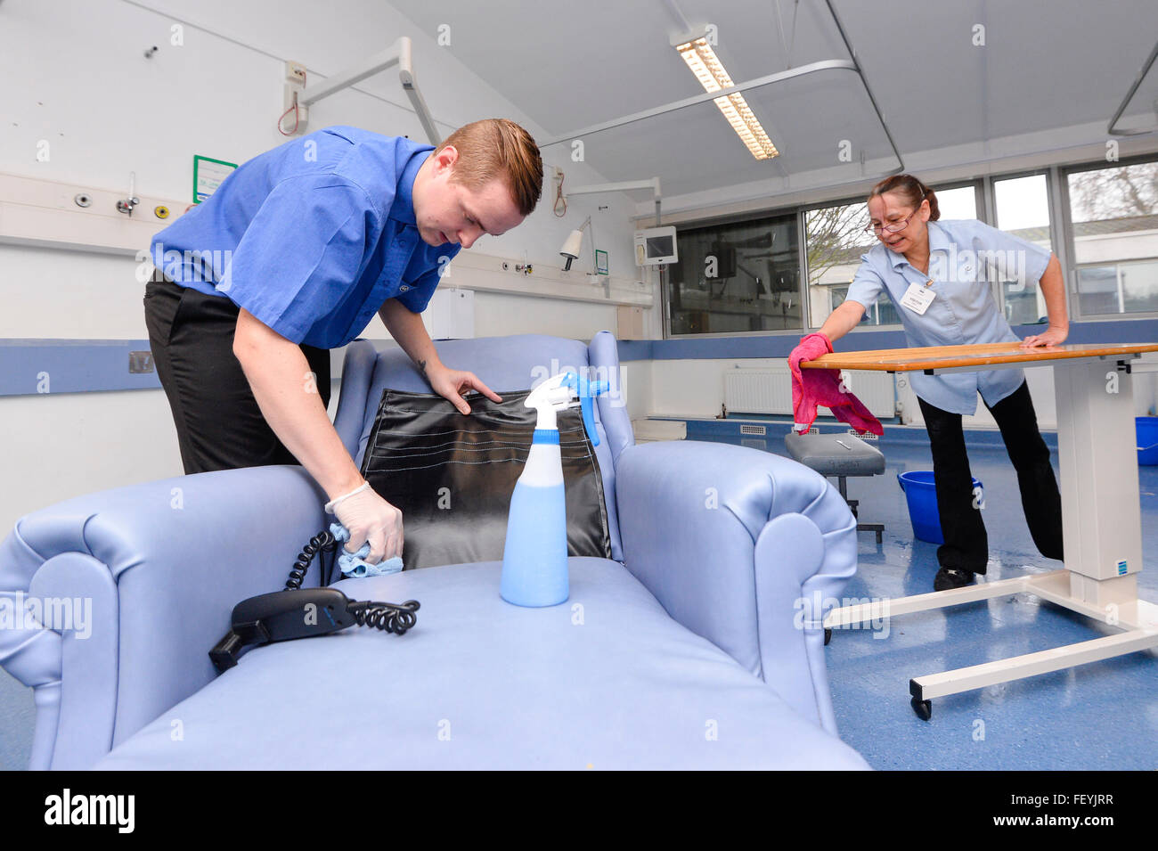 Un equipo de limpieza profesional matorrales, spray y limpie todas las superficies en salas de hospital. Crédito: Euan Cherry Foto de stock