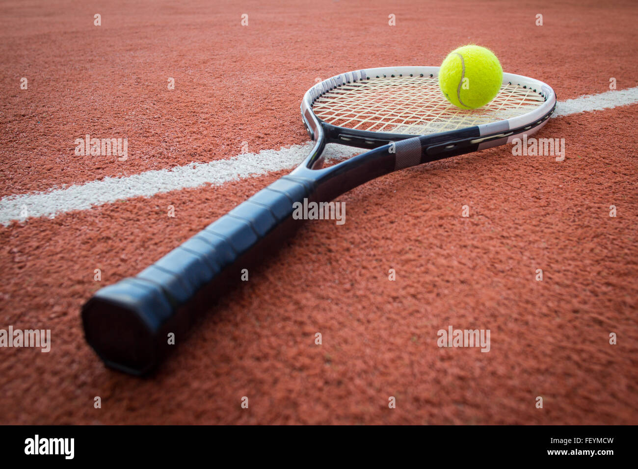 Raqueta de tenis cerca de una bola amarilla con un ladrillo rojo corte Foto de stock