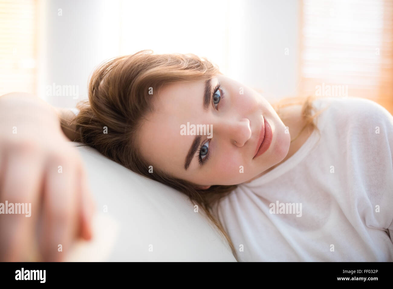 Sonriendo Pretty Woman colocando su cabeza en el sofá Foto de stock