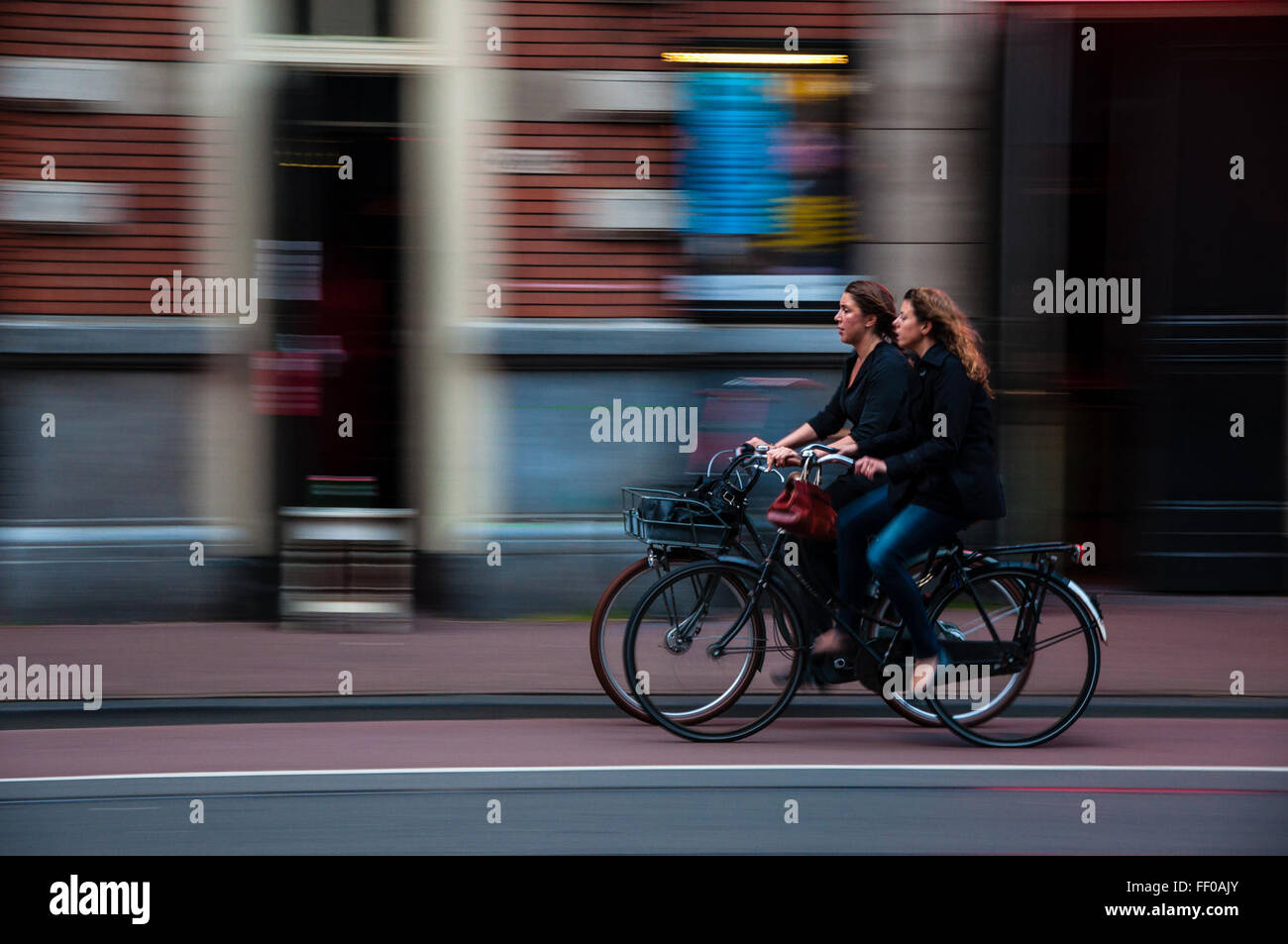 Los ciclistas femeninos cabalgando al lado de los ciclistas femeninos al lado de equitación Foto de stock