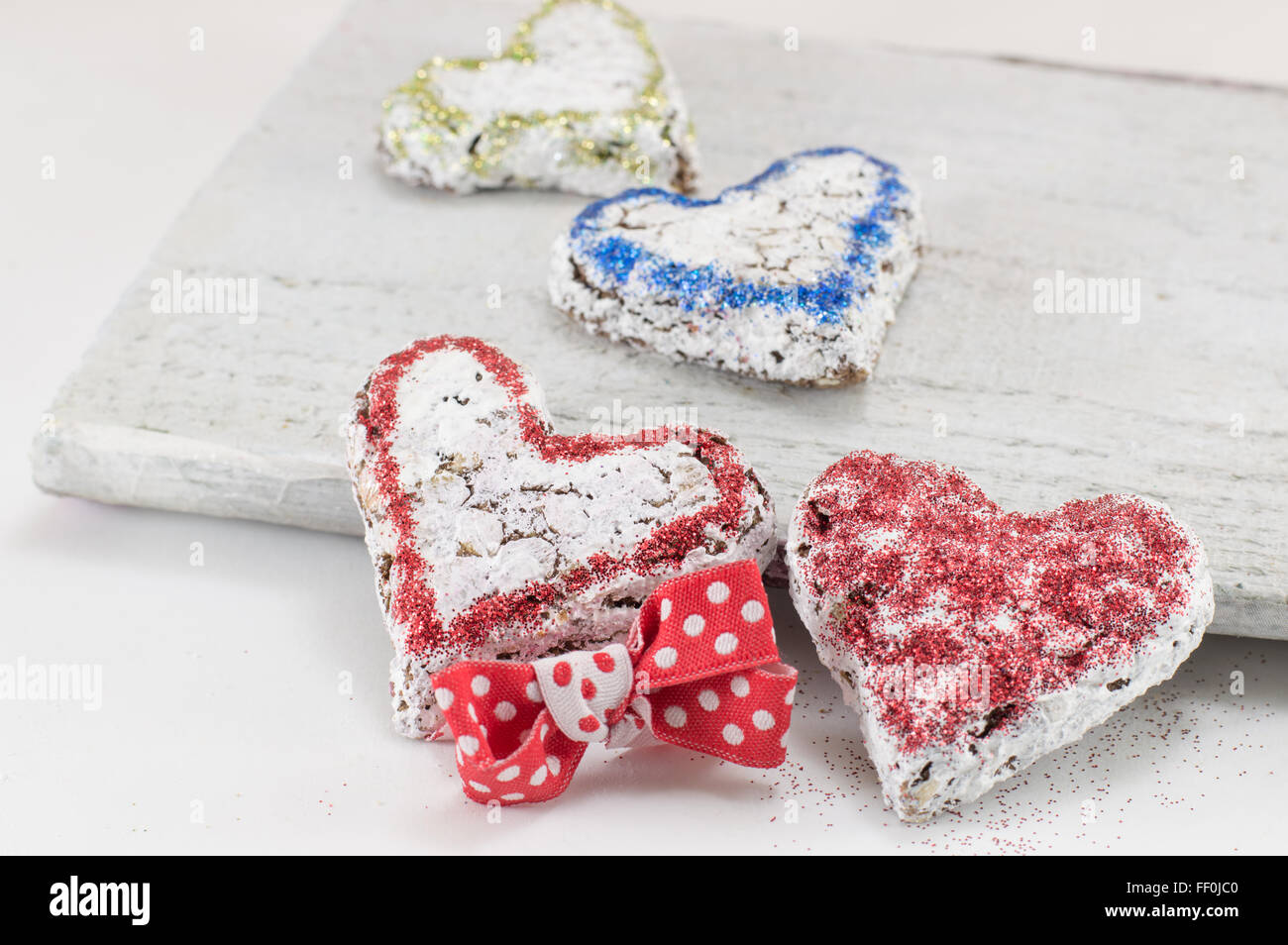 Galletas dulces en forma de corazón en una placa de madera blanca Foto de stock