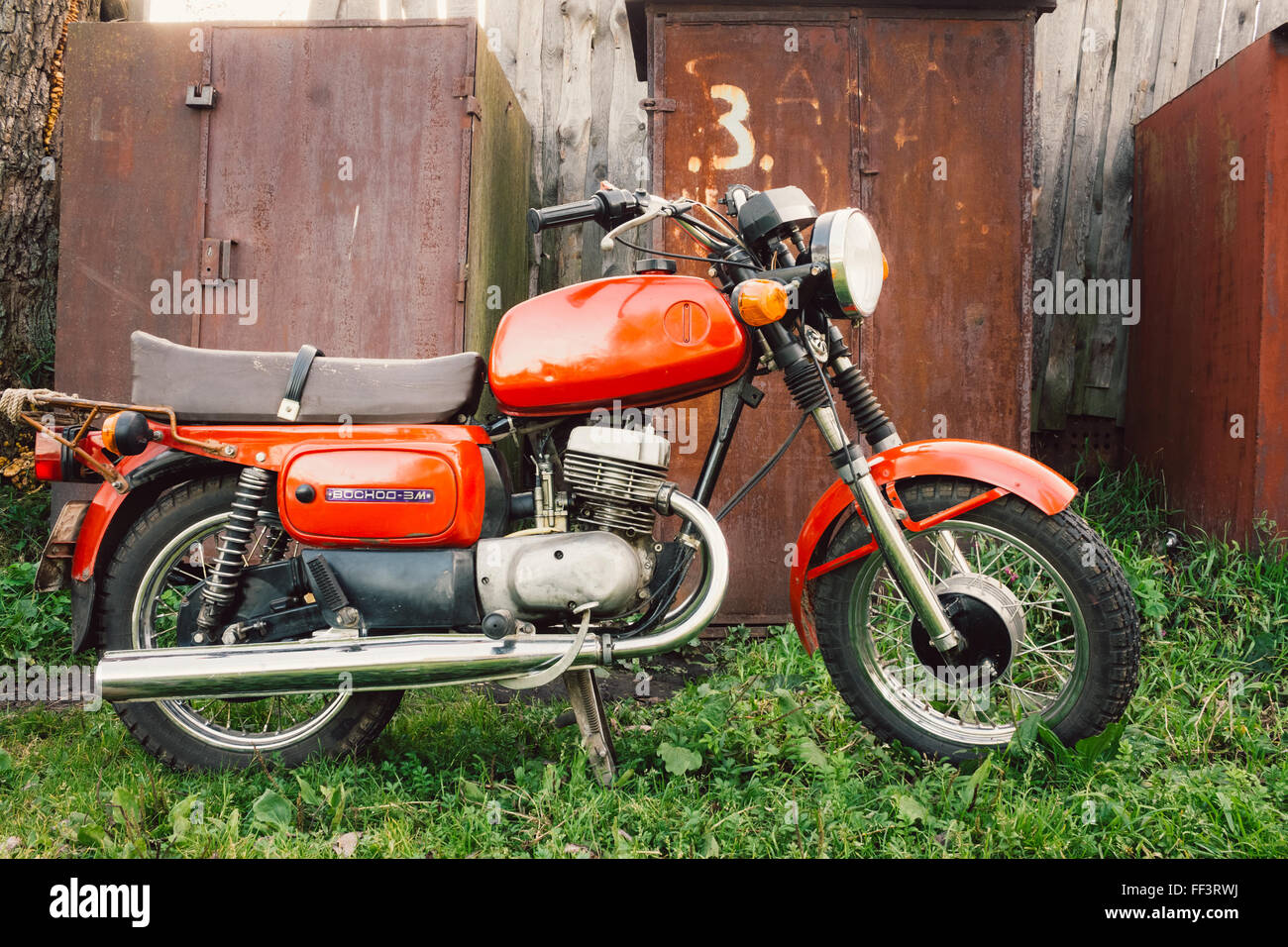 MINSK, BIELORRUSIA - Septiembre 22, 2013: Viejo Rojo Ruso (Soviético) Moto 'Voshod" estacionado en el pasto verde patio. Este motocicletas Foto de stock
