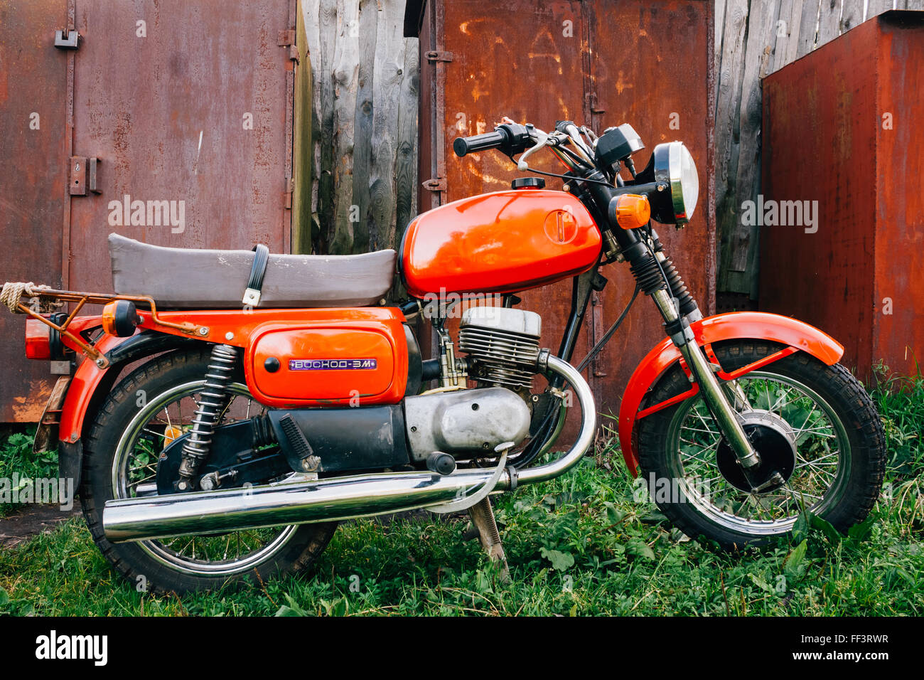 MINSK, BIELORRUSIA - Septiembre 22, 2013: Viejo Rojo Ruso (Soviético) Moto 'Voshod" estacionado en el pasto verde patio. Este motocicletas p Foto de stock