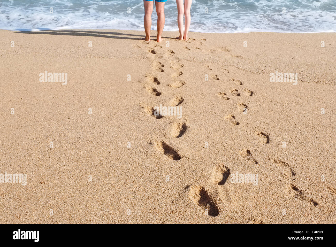 Las piernas masculinas y femeninas en la playa cerca de agua de mar Foto de stock