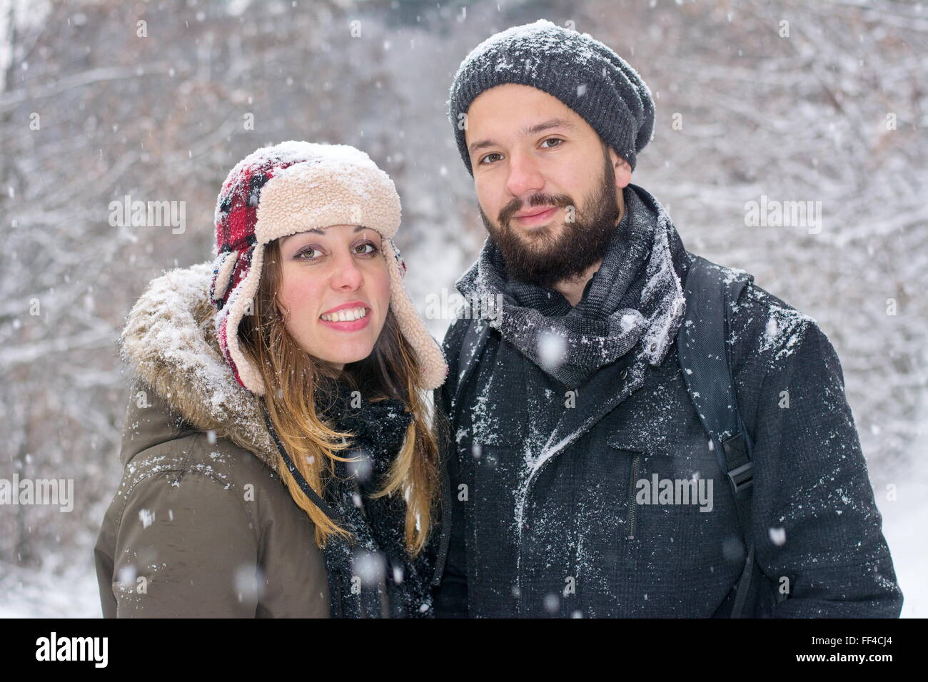 Chico y chica brunetet barbudo posando en la nieve Foto de stock