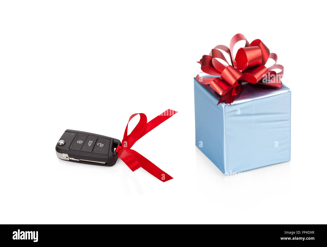 Concepto de regalo: las llaves del coche con caja de regalo azul con una cinta roja aislado en blanco Foto de stock