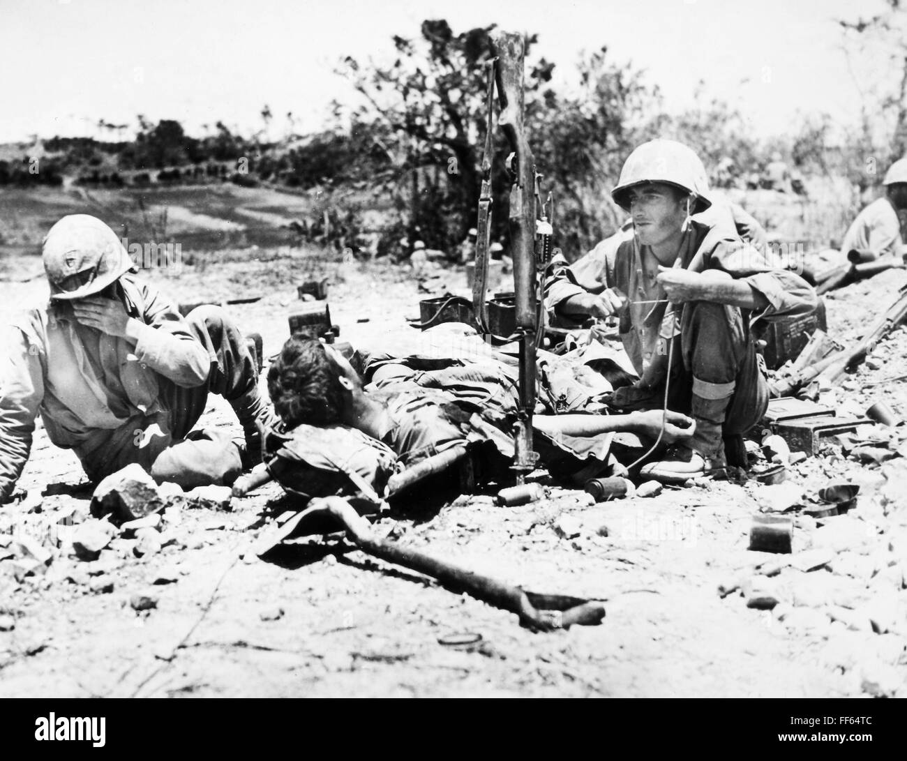 La SEGUNDA GUERRA MUNDIAL: Okinawa. /NA ayudante médico del hospital de la Marina de EE.UU. administra el plasma sanguíneo, utilizando su rifle como apoyo, a un infante de Marina herido en Okinawa, en mayo de 1945. Foto de stock