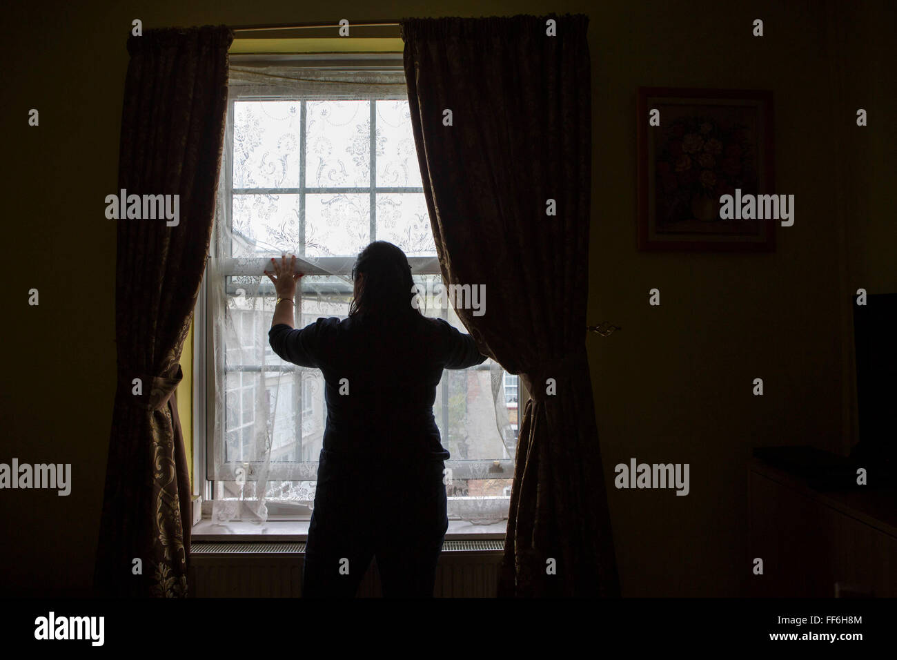 Una dama no identificada está silueteado en frente de su salón Cristal. El aislamiento y los problemas de salud mental en Londres, Reino Unido. Foto de stock