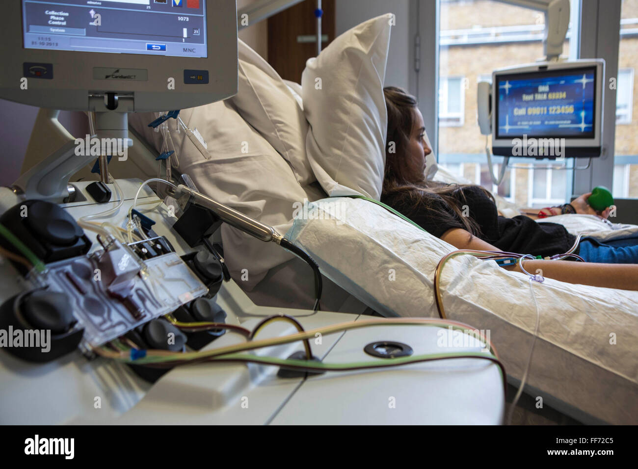 Una joven paciente del hospital se encuentra la cama mientras estaba conectado a un dispositivo de transfusión médica en la clínica de Londres, Londres, Reino Unido. Sus células madre están siendo recopilados a través del separador celular equipos que ella está donando para un trasplante alogénico de células madre para alguien con problemas graves de cáncer de la sangre (leucemia, linfoma y mieloma). Ella es la más joven de los donantes no relacionados en el Reino Unido. Foto de stock