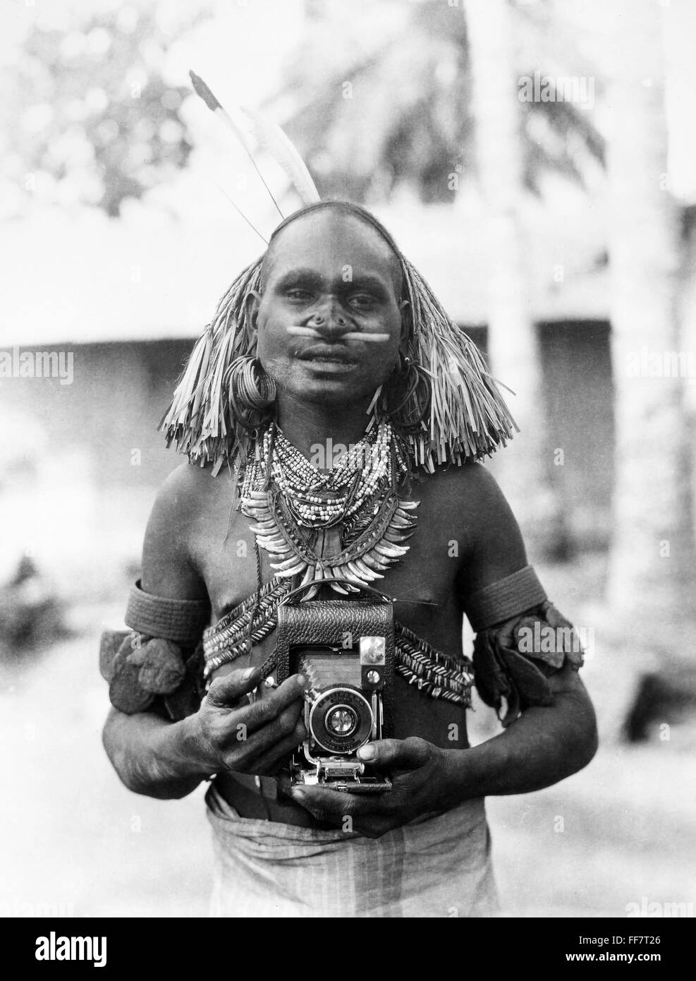 Fotógrafo, c1930. /NA, posiblemente nativo de Nueva Guinea, con una Kodak plegables, c1930. Foto de stock