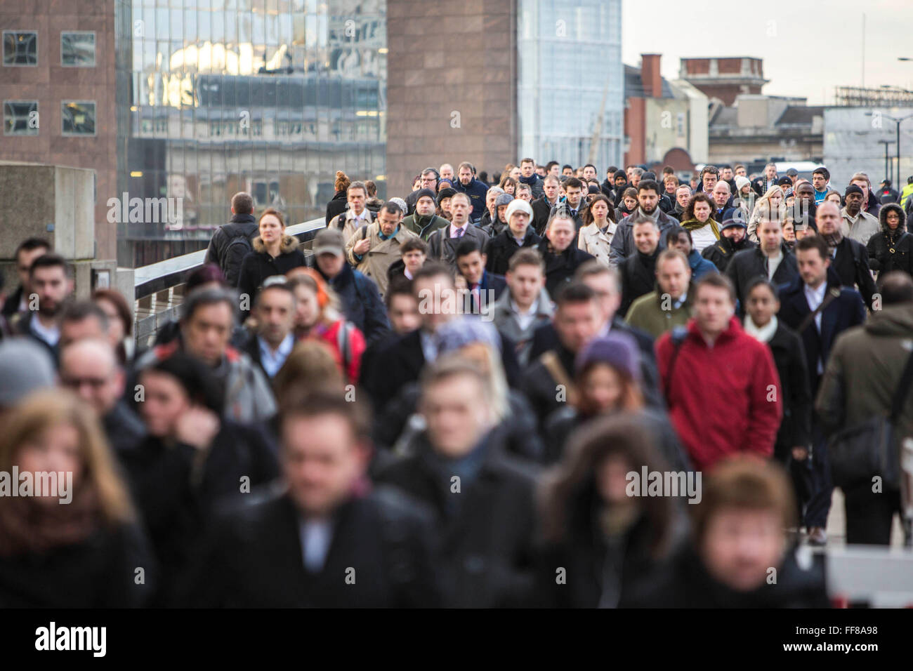 Los viajeros a pie cruzando el puente de Londres para empezar a trabajar en la ciudad de Londres, Reino Unido. Miles de viajeros llegan a la estación de London Bridge y cotidiana a pie de obra. Foto de stock
