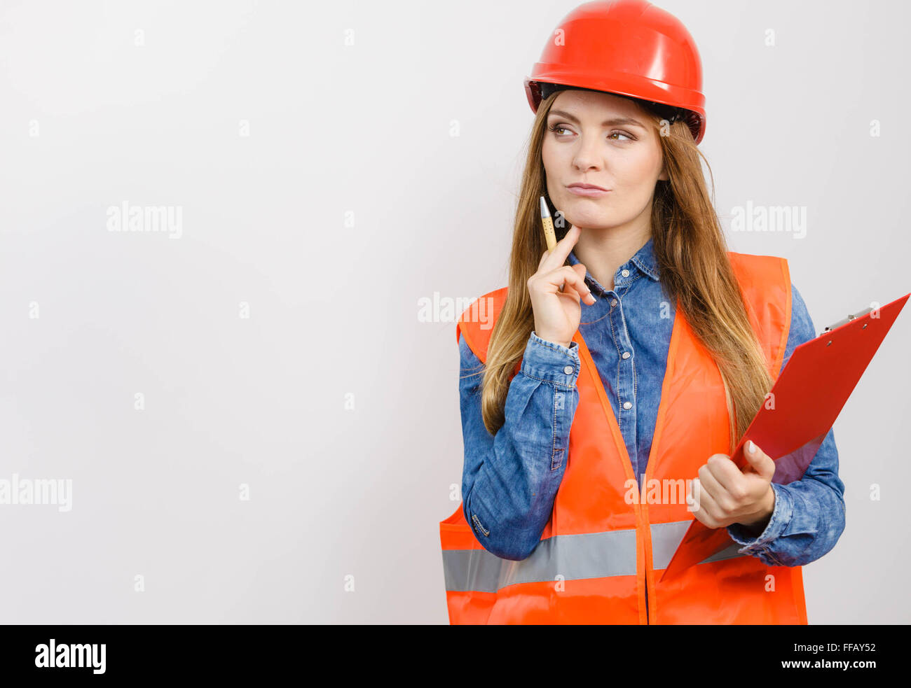 Mujer, trabajador de la construcción estructural generador engineerin en chaleco anaranjado rojo casco duro contiene archivo pen pad. Seguridad industrial Foto de stock