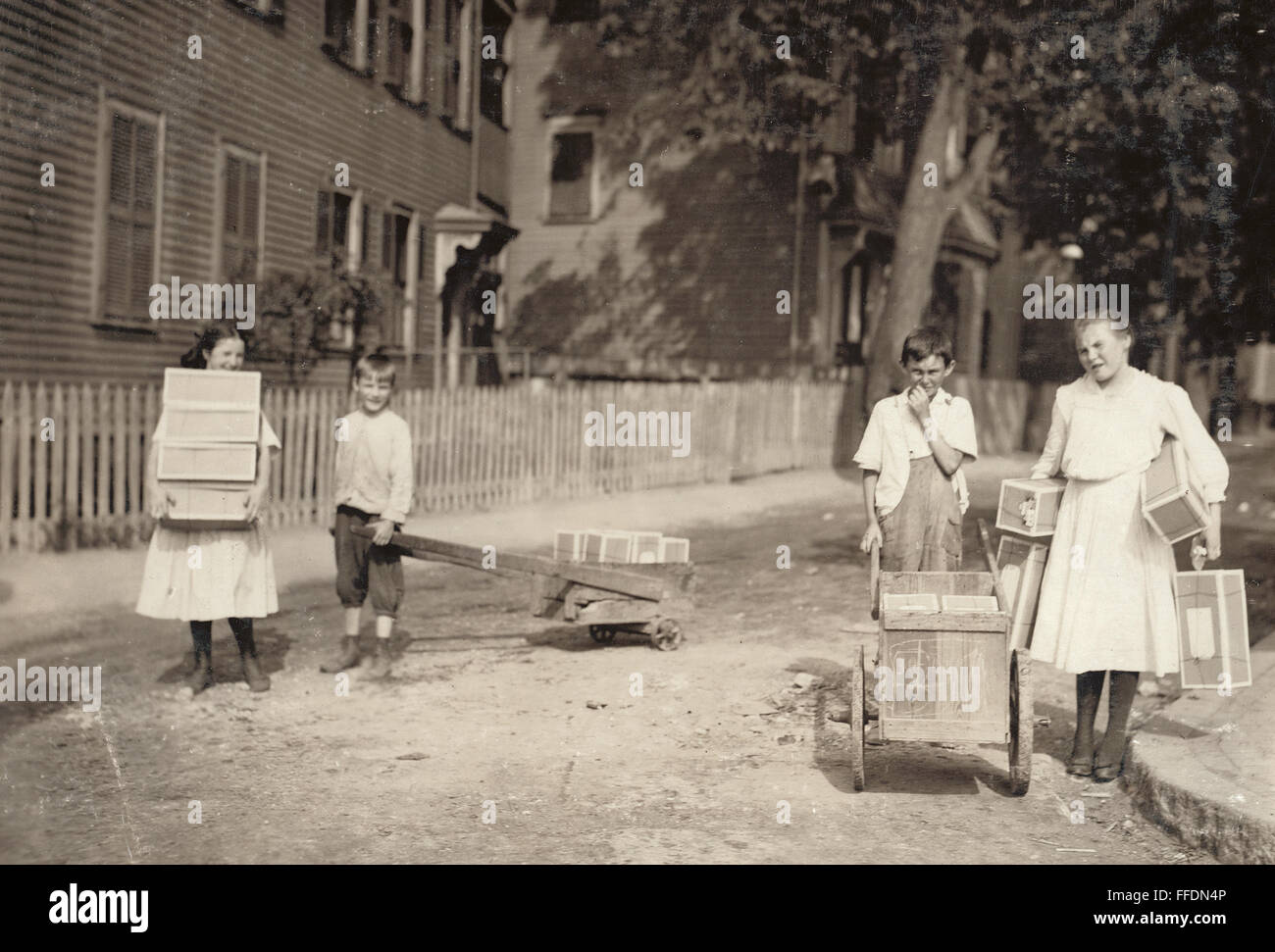 La familia de los trabajadores, 1912. /NA familia en Roxbury, Massachusetts, portando etiquetas de inicio a una cadena de trabajo. Fotografía de Lewis Hine, agosto de 1912. Foto de stock