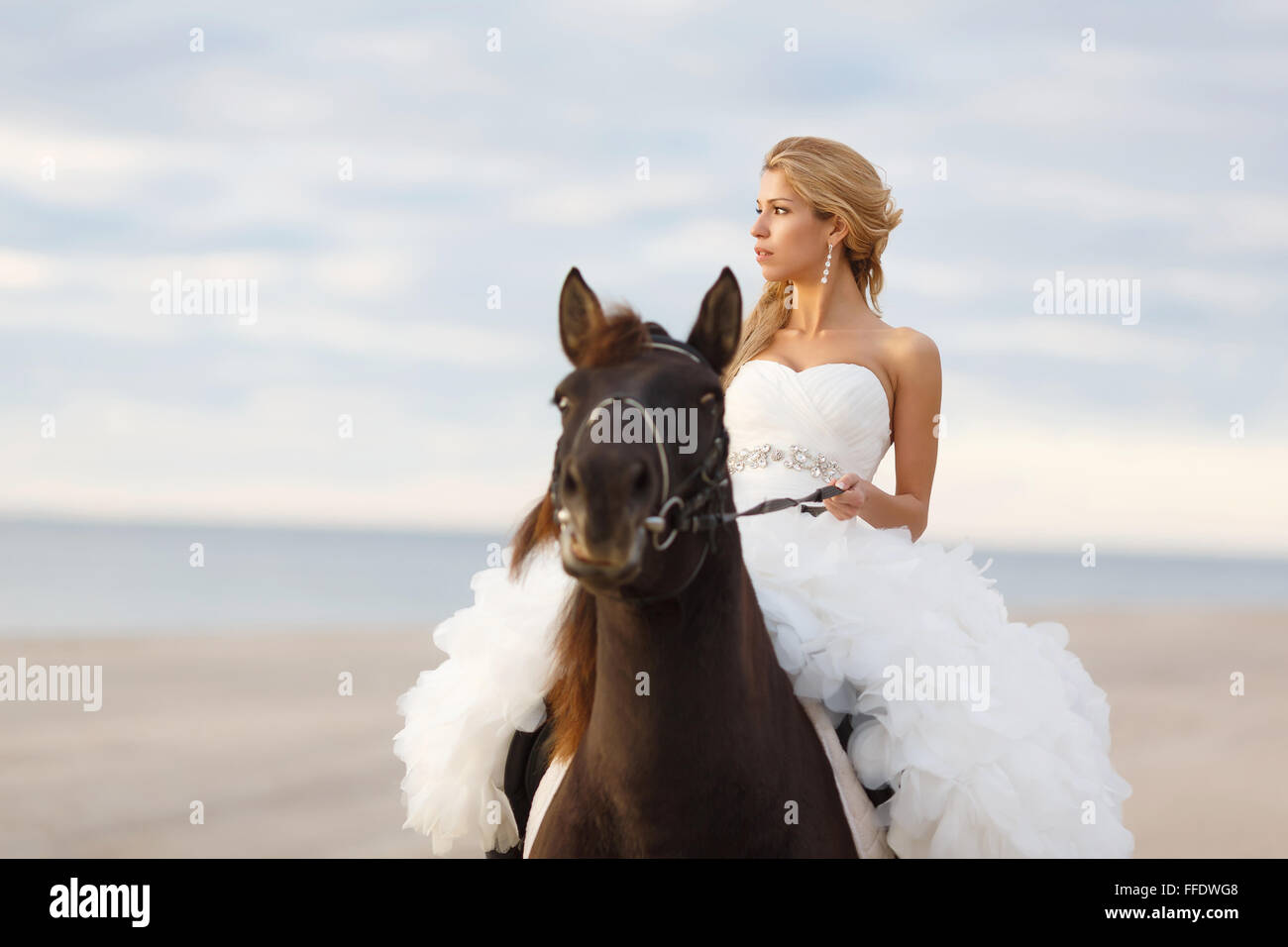 Novia en un caballo por el mar en su día de la boda Foto de stock