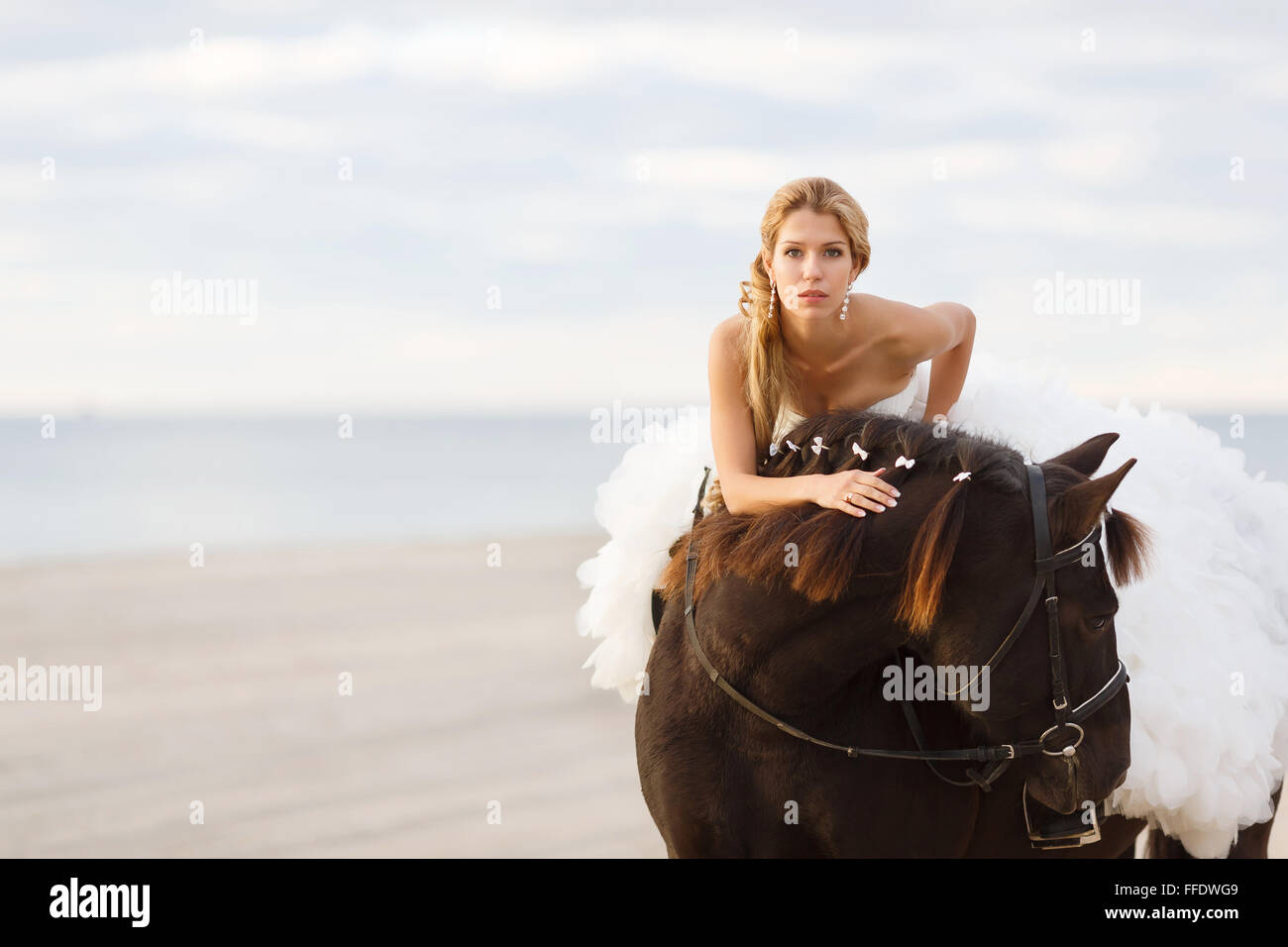 Novia en un caballo por el mar en su día de la boda Foto de stock