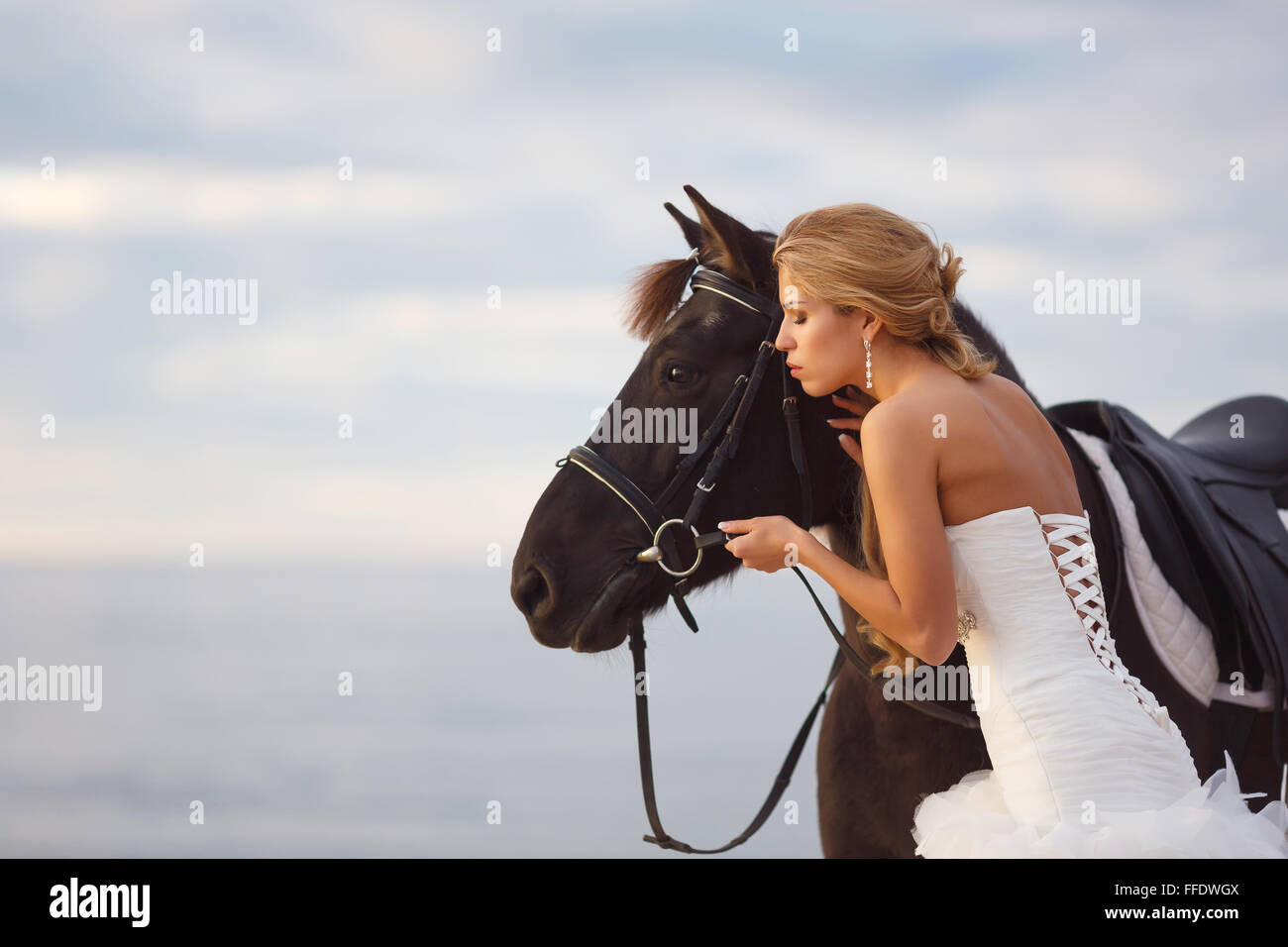 Novia con un caballo por el mar en su día de la boda Foto de stock