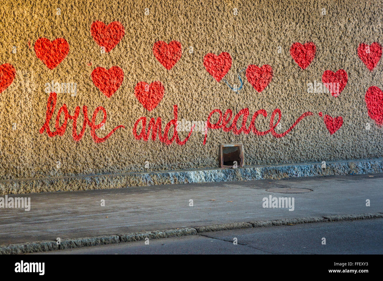 Grafito en un paso subterráneo mostrando Corazones rojos y el texto: el amor y la paz Foto de stock