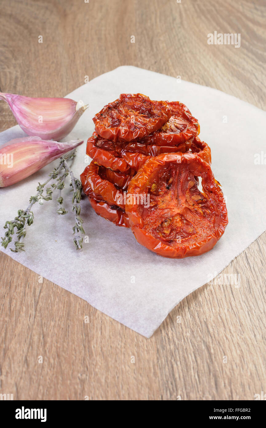 Montón de tomates secos apilados en un papel para hornear con comino y ajo. Foto de stock