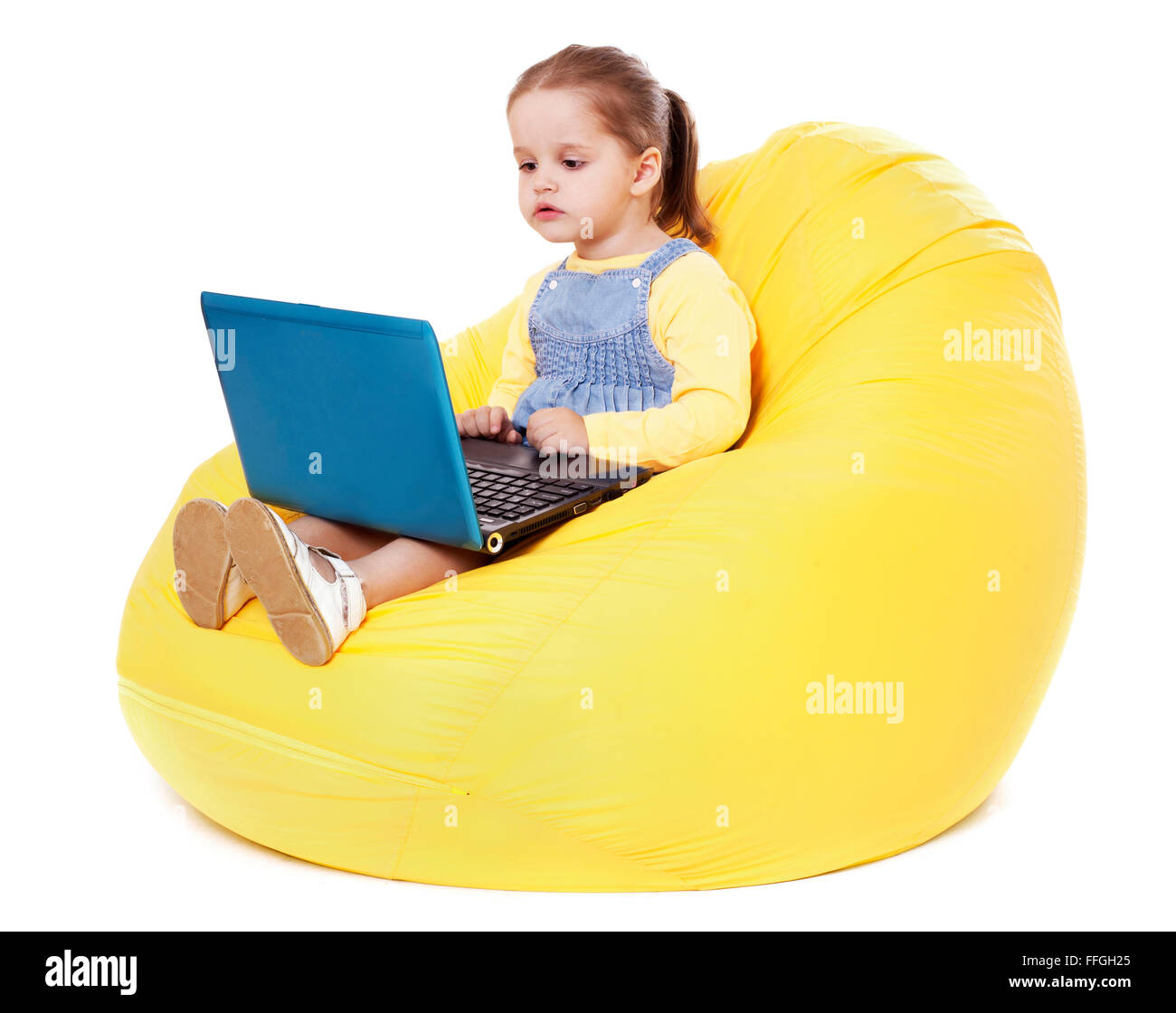 Niña sentada en un bean bag con portátil - Stock Image Foto de stock