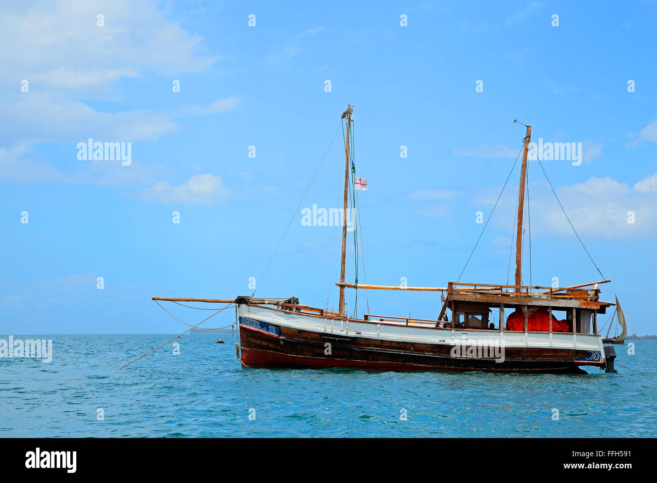 Barco de madera flotando sobre las aguas cristalinas de color turquesa de la isla de Zanzíbar Foto de stock