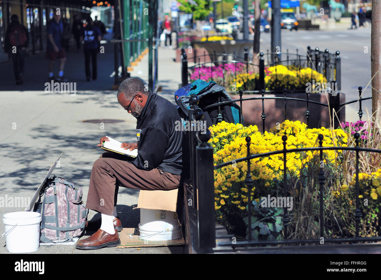 Hombre con una estaca a la sección de Chicago del prestigioso south Michigan Avenue pasando el tiempo leyendo en un banco. Chicago, Illinois, Estados Unidos. Foto de stock