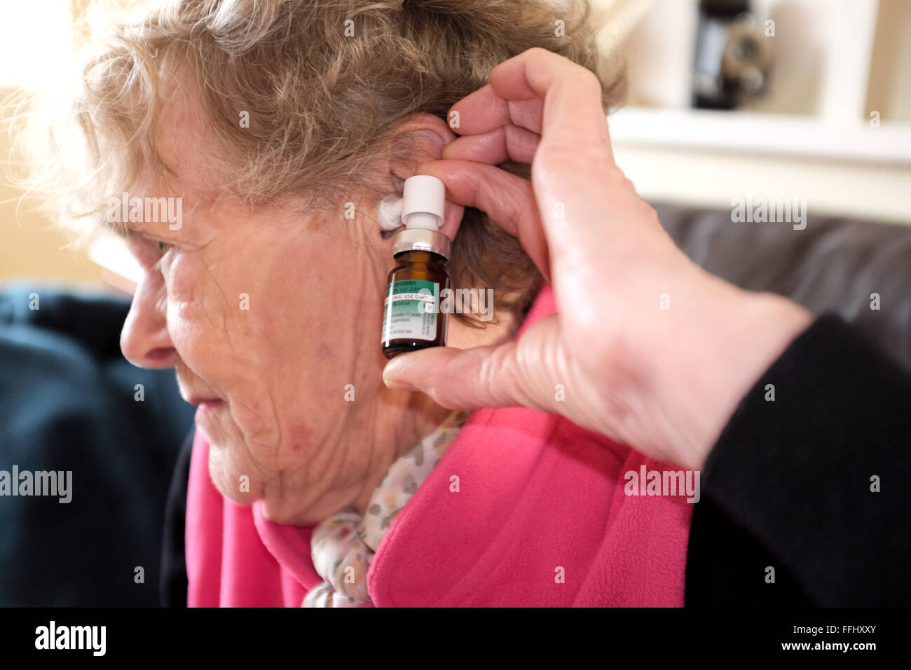 Anciana con aerosol para ayudar a calmar el oído con un dolor de oído dolor de oído salud Foto de stock