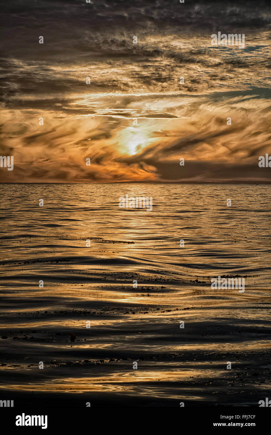 Una espectacular puesta de sol sobre el océano en California revela los complejos patrones de nubes que cubren la puesta de sol. Foto de stock