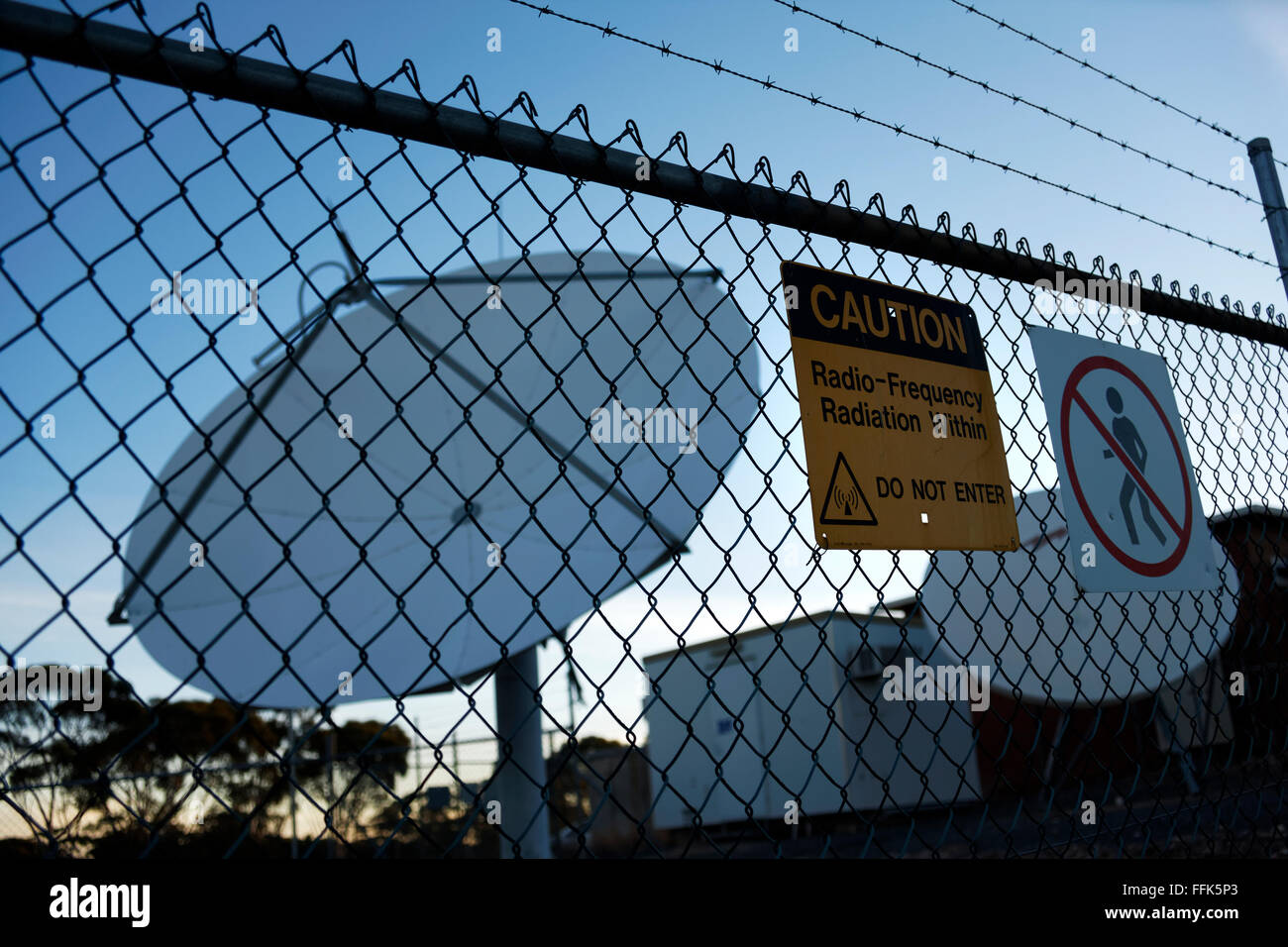 Señal de alerta de radiación en el cerco con Antena Parabólica, Norseman, Australia Occidental Foto de stock