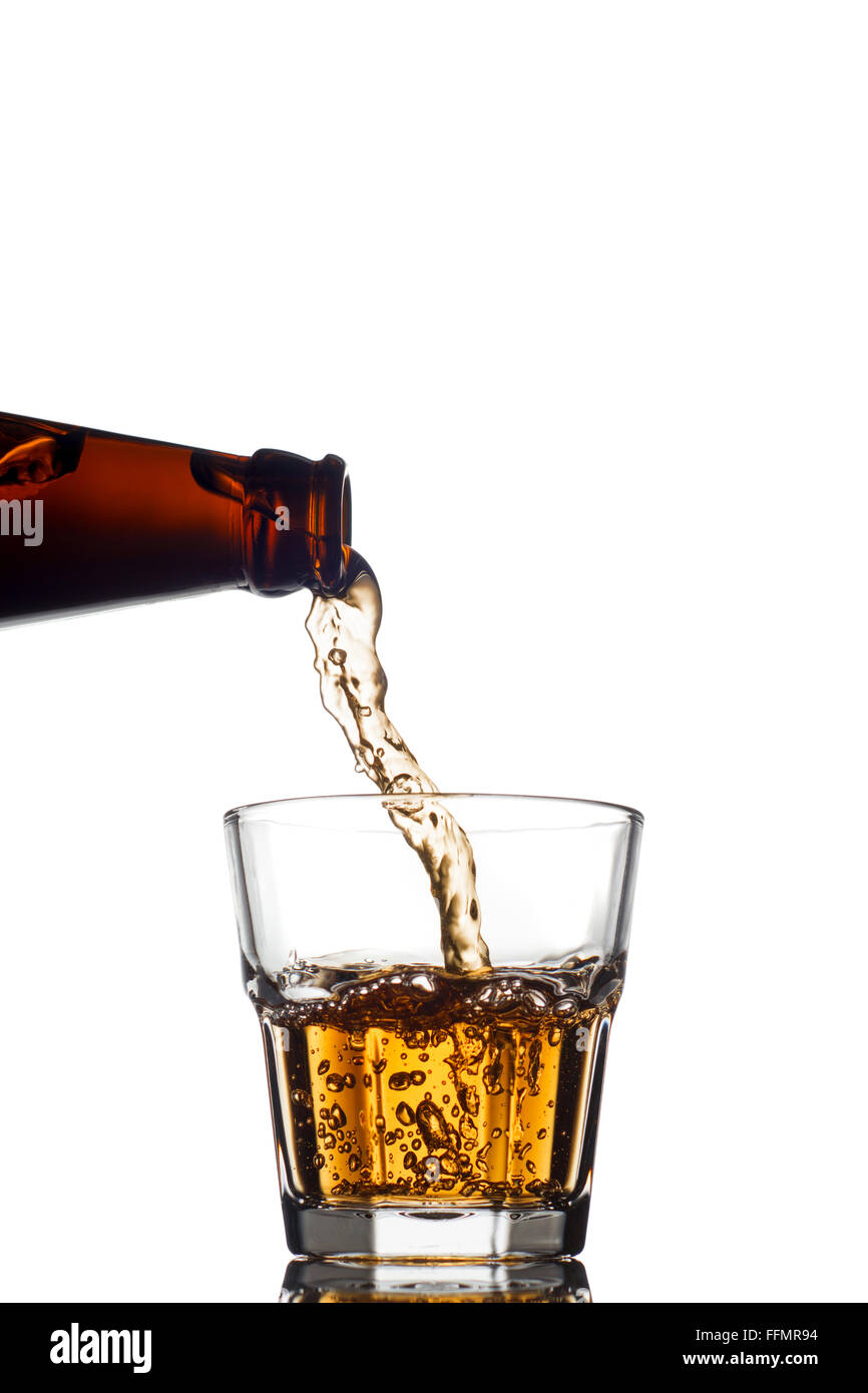 Verter el whisky en un vidrio claro, sobre fondo blanco. Foto de stock