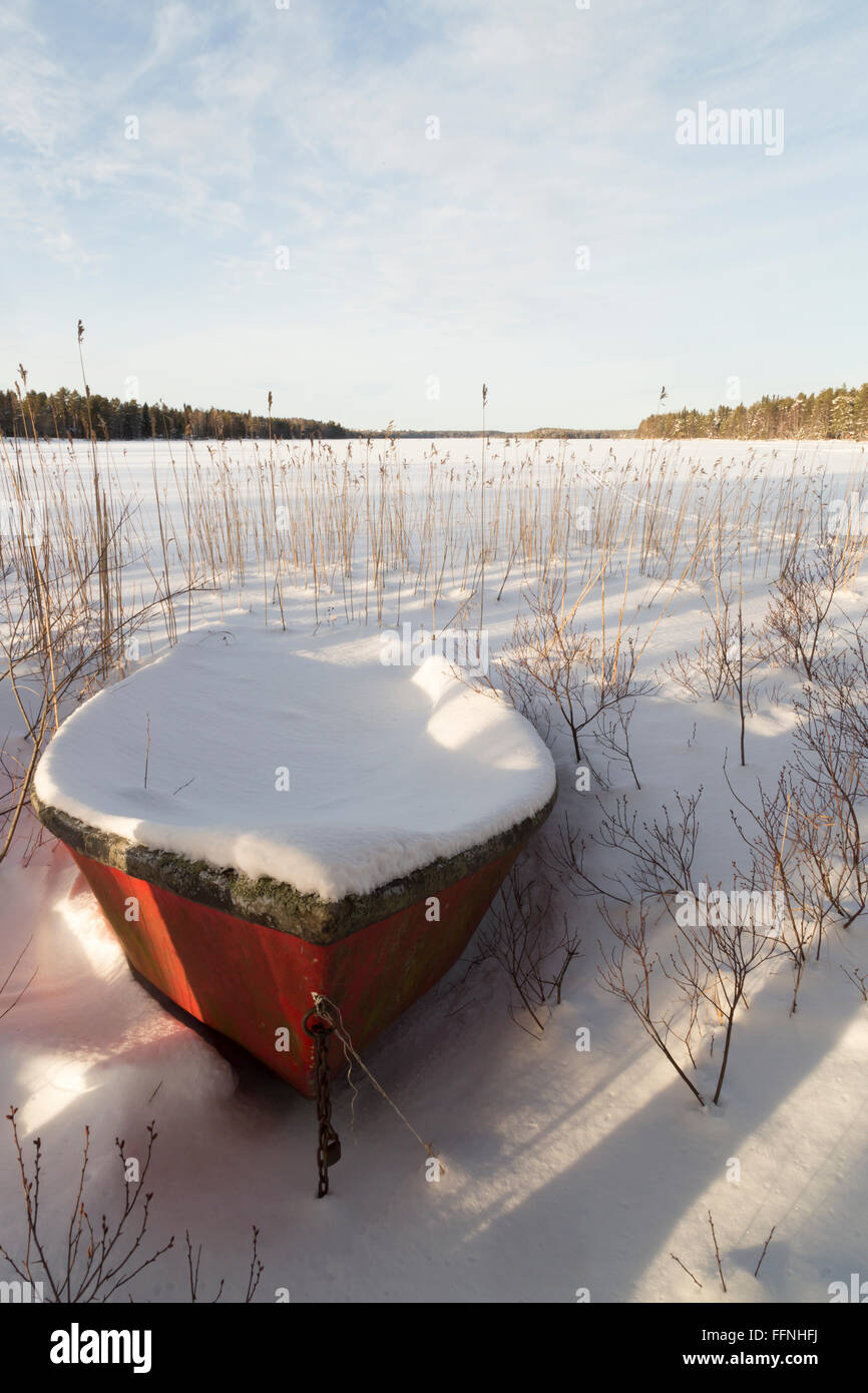 Botes cubiertos de nieve por el lago Foto de stock