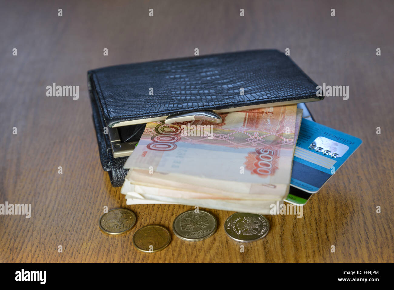Billetera con tarjetas de crédito y el dinero acostado sobre una mesa de madera Foto de stock