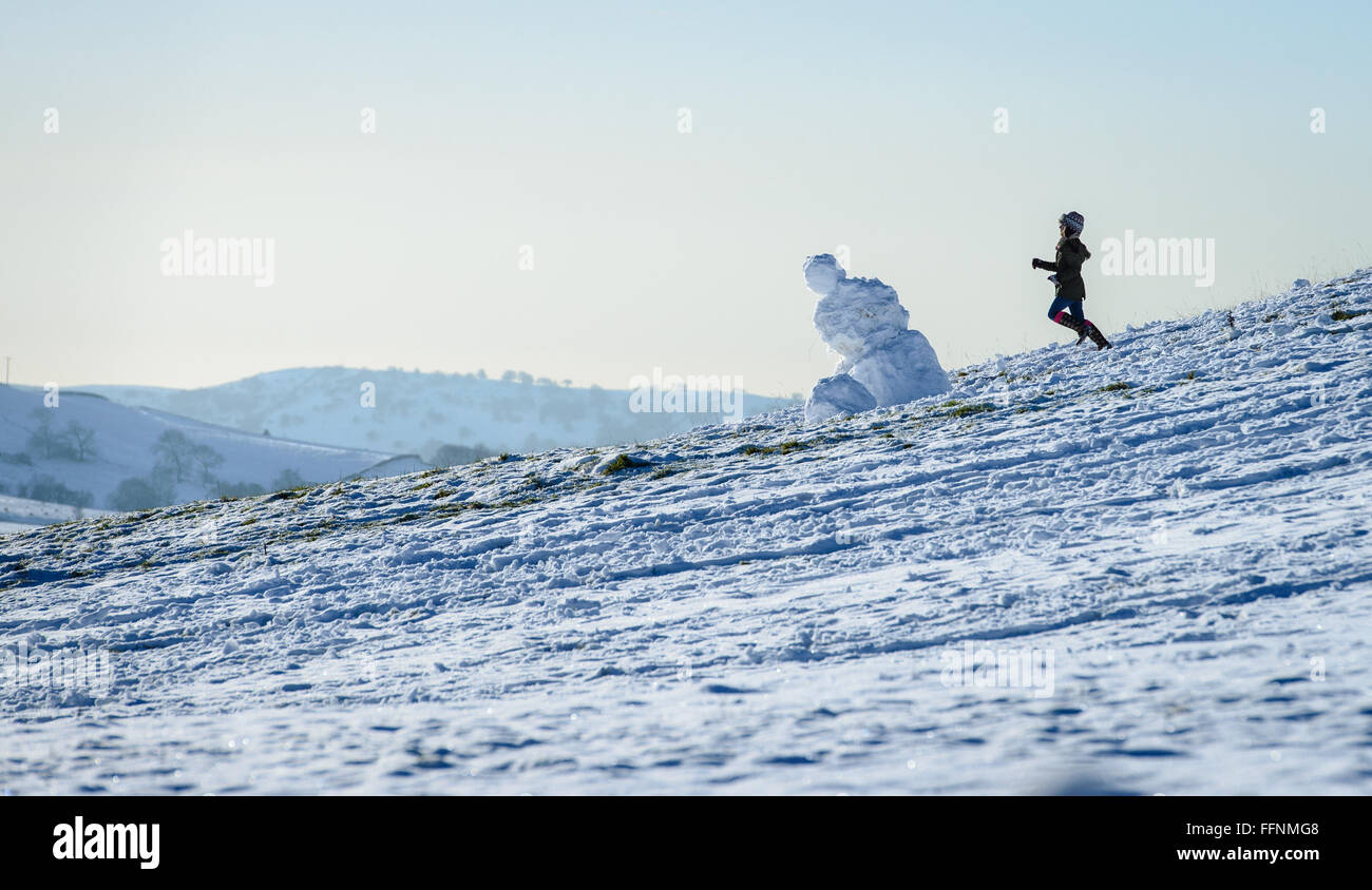 Niña corriendo por una ladera cubierta de nieve, pasado un muñeco de nieve  inclinada Fotografía de stock - Alamy