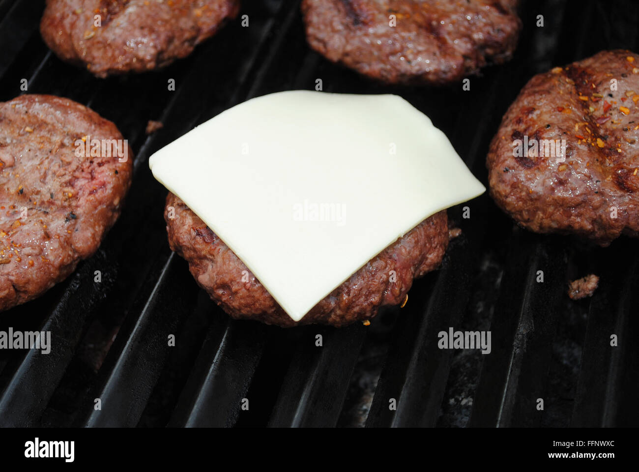 Fusión de queso americano en primer plano sobre una hamburguesa de carne Foto de stock