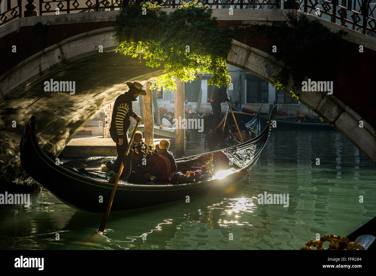 Canal, góndola con gondolero viaja bajo un puente, Venecia, Véneto, Italia Foto de stock