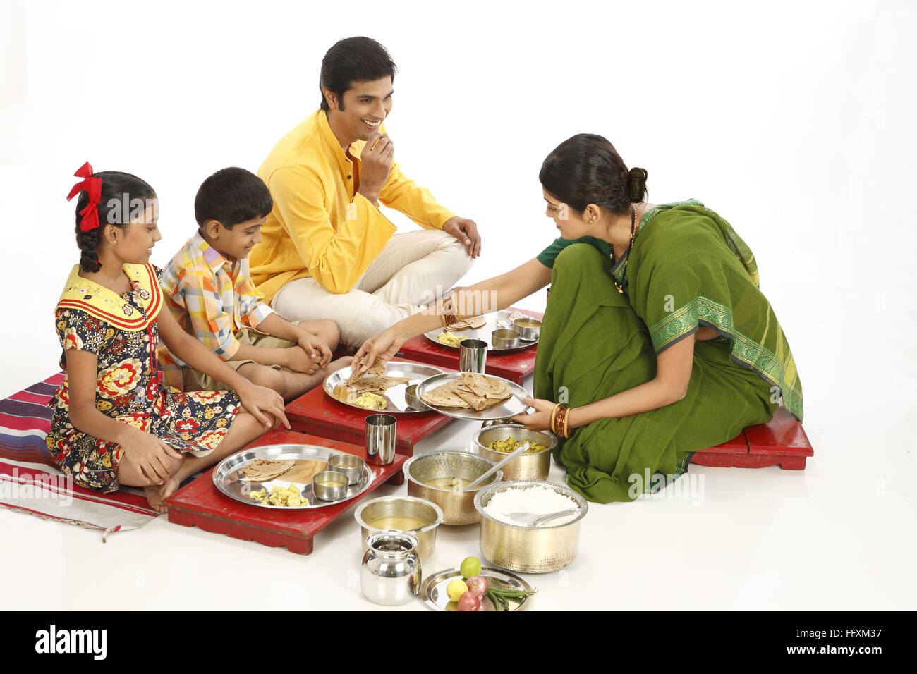 El padre y los hijos comiendo alimentos y madre sirviendo roti a hijo señor#743A, 743B, 743C, 743D Foto de stock