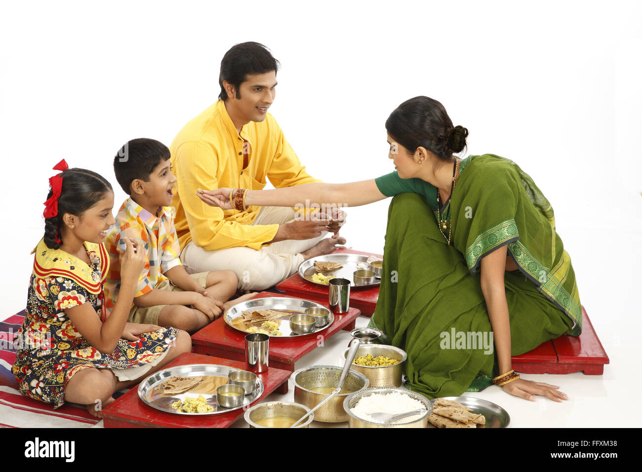 Familia india comiendo el almuerzo, padre y dos niños comiendo la comida y madre alimentando hijo, India, Asia, MR#743A,743B,743C,743D Foto de stock
