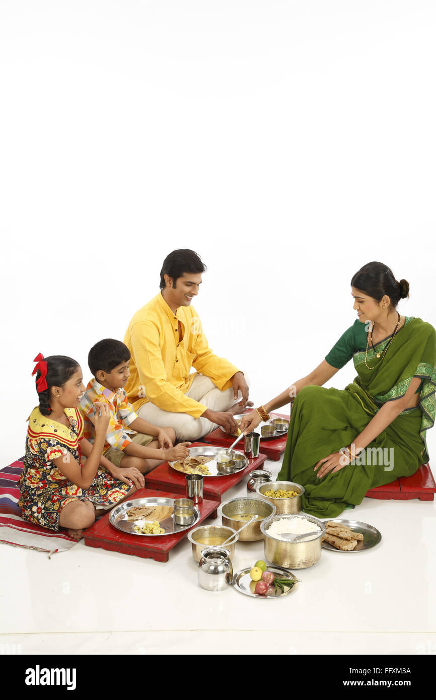 El padre y los hijos comiendo alimentos y madre sirviendo a hijo señor#743A, 743B, 743C, 743D Foto de stock