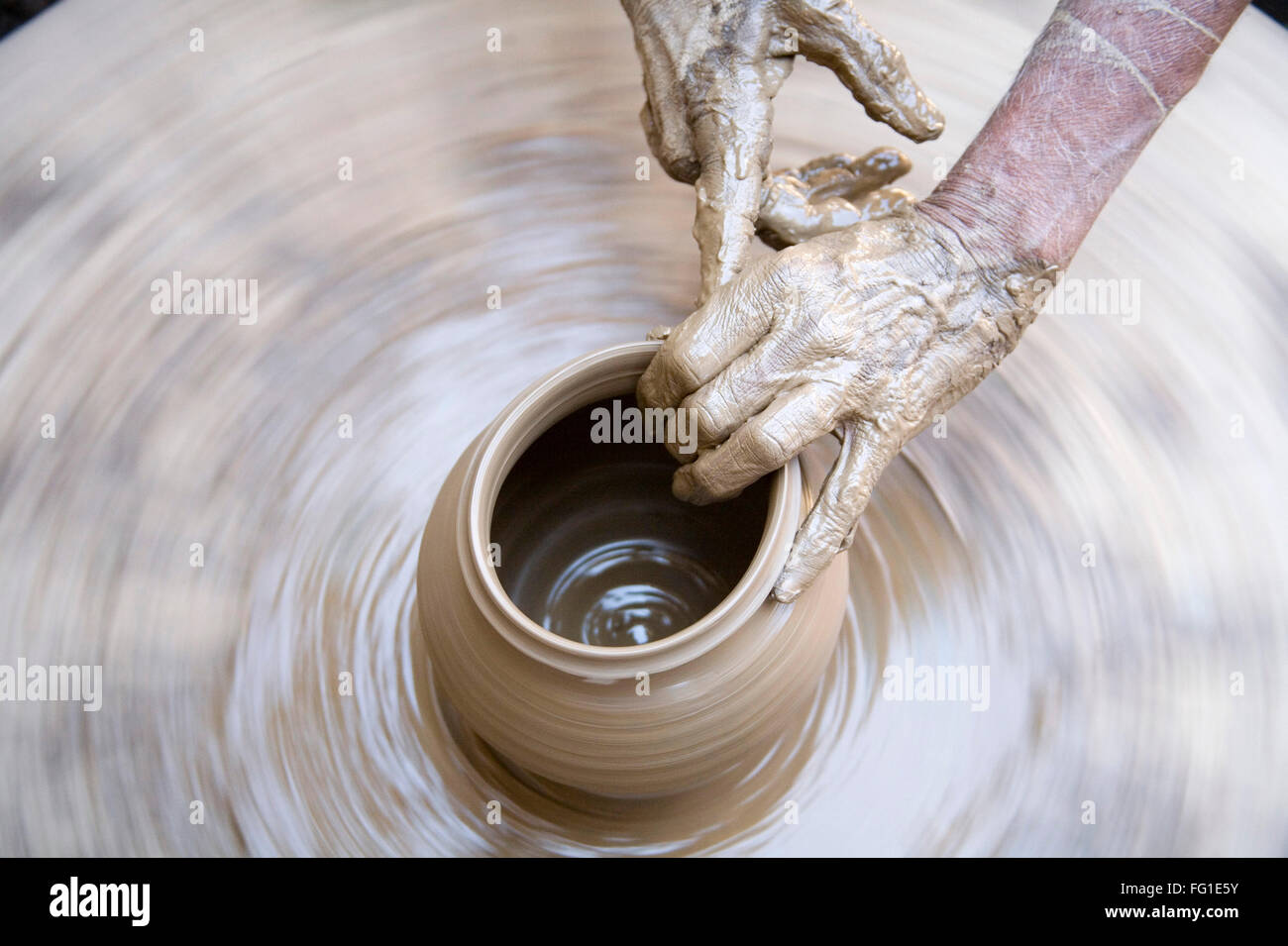 Alfarería , alfarero manos fangosas haciendo olla de arcilla dando forma a la rueda giratoria , Dilwara , Udaipur , Rajastán , India , Asia Foto de stock