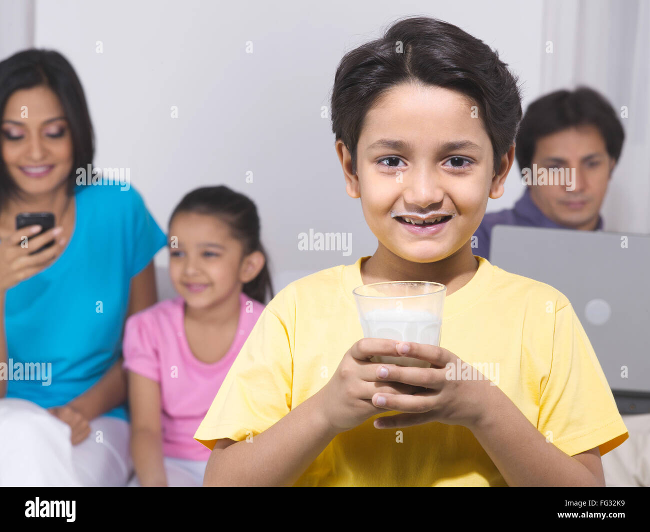 Niño sosteniendo un vaso con su familia en el fondo el Sr.#779P ; Señor#779P ; Señor#779R ; Señor#779S Foto de stock