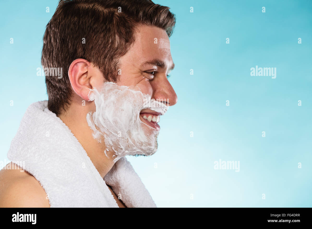 Joven con espuma de crema de afeitar y una toalla blanca. Guapo preparando  para afeitarse. El cuidado y la higiene de la piel Fotografía de stock -  Alamy