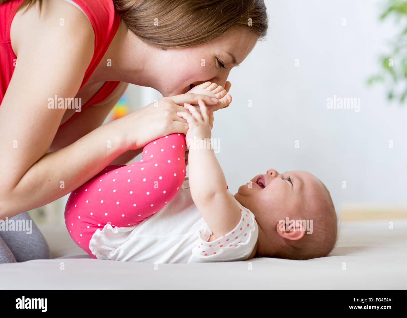 Madre gozosa jugando con el bebé lactante Foto de stock