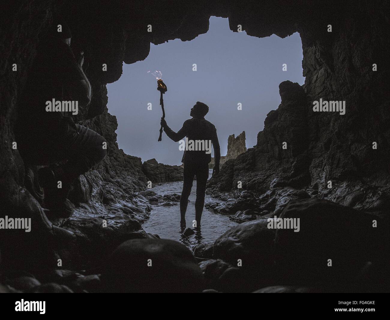 Hombre con antorchas caminando en una cueva. Foto de stock