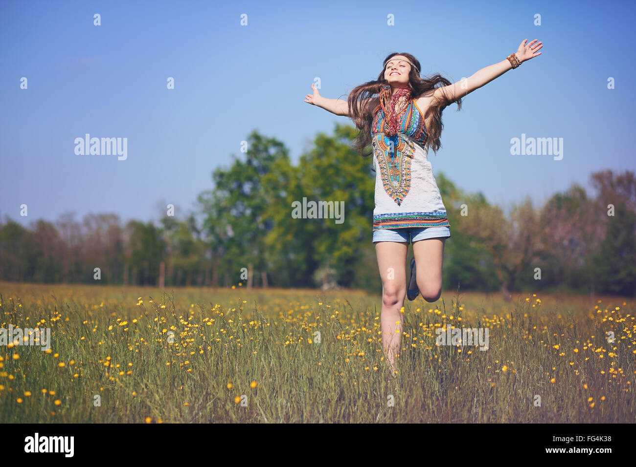 Feliz y sonriente mujer hippie salta en un campo de verano . Vintage efecto fotográfico. Foto de stock