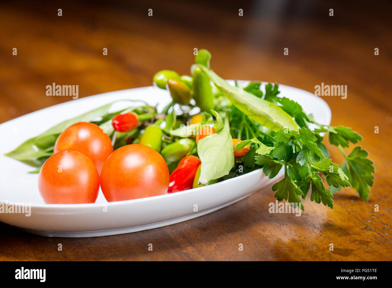 Tomates y pimientos picantes con perejil fresco del jardín Foto de stock